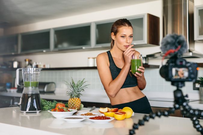 Fit female taking a sip of her fruit juice in front of camera
