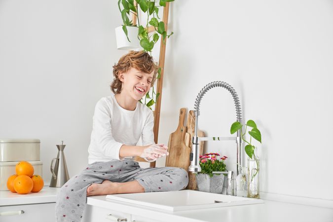 Cheerful boy washing hands with pleasure