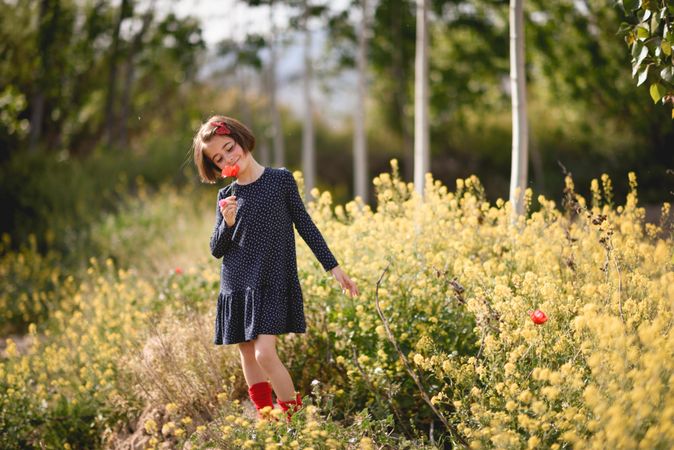 Child smelling a flower in a beautiful field surrounded by yellow flowers