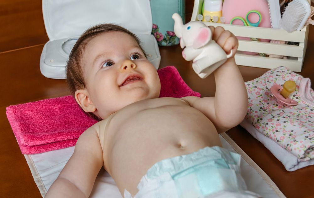 Adorable baby lying smiling and playing with a rubber toy