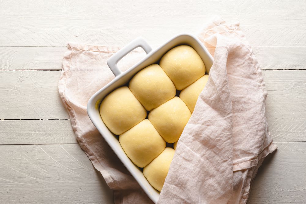 Uncooked bread buns in a ceramic tray