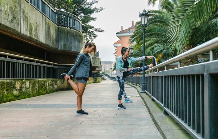 Women runners stretching legs before training in town