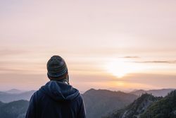 Warmly dressed person looking at sunrise in mountain
