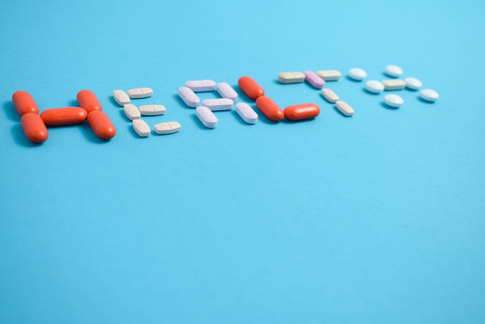 Multiple pills spelling the word "HEALTH" on blue background with copy space