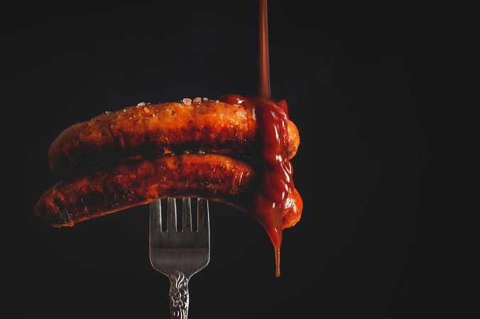 ketchup falling on grilled sausages