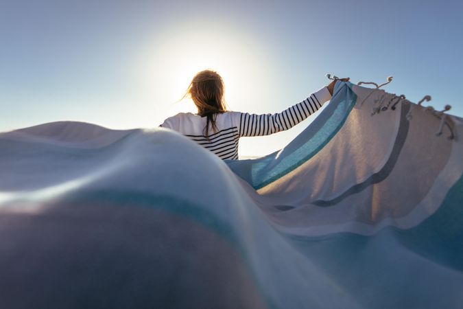 Woman holding a blanket with sun flare in the background
