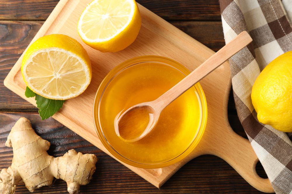 Honey, ginger, lemons and towel on wooden background, top view
