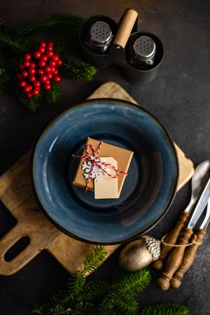 Navy plate with present, on table with Christmas pine