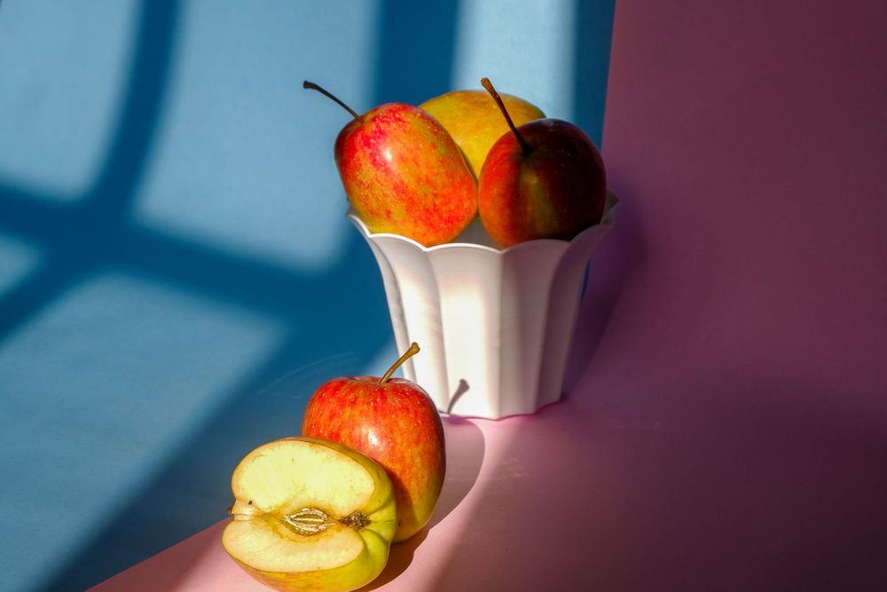 Photo of an apple in a container on a pink and blue background