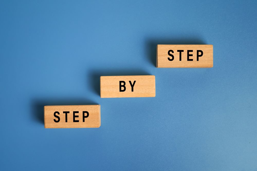 step by step word on wooden blocks staircase isolated on blue background. concept of success progress or career