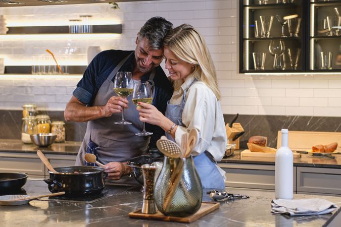 Happy couple clinking glasses in kitchen