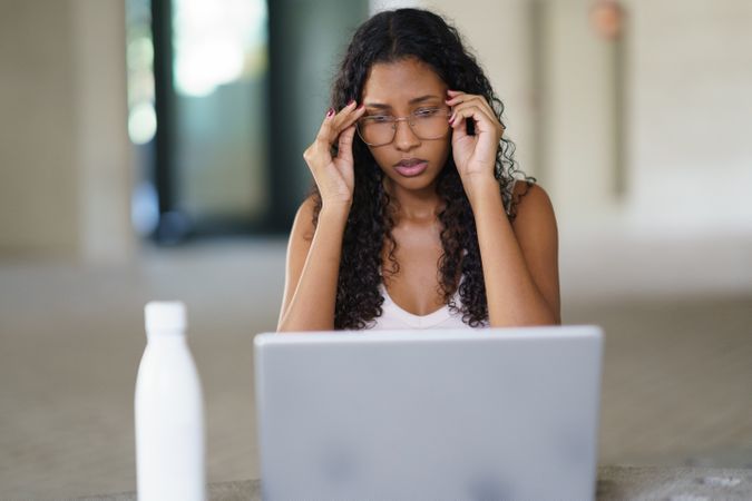 A stressed woman is diligently working on her laptop in a modern and stylish workspace