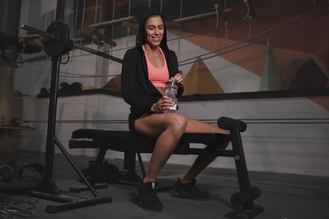 Smiling woman with bottle of water in gym