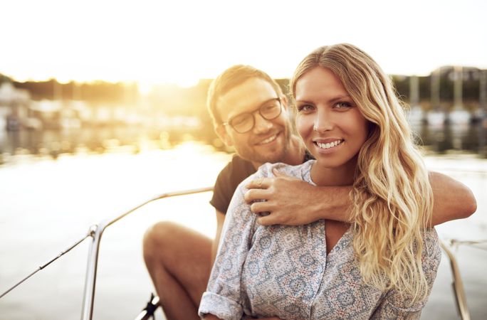 Happy couple sitting on boat at sunset