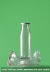 Glass over plastic bottles concept on a green background 41PJD5