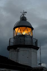 Shining lighthouse against cloudy sky