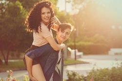 Curly haired girl on boyfriends back in park