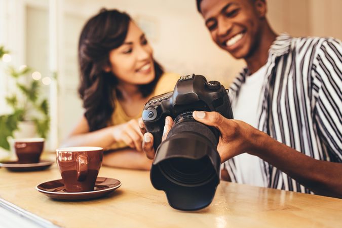 Man showing his new content to female on dslr camera at cafe