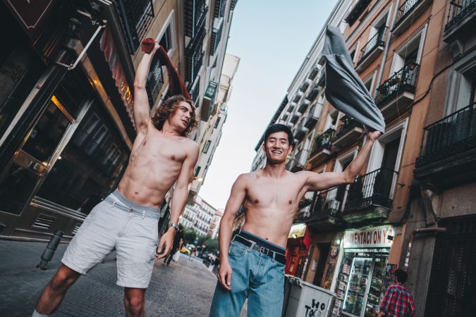 Rebellious shirtless multiracial men shouting while standing together on city street