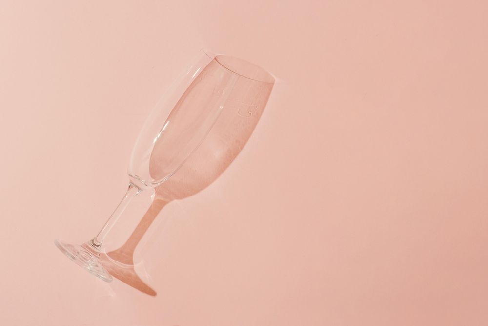 Champagne glass on pastel coral background