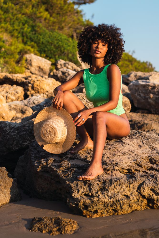 Black woman in swimsuit and with hat on beach