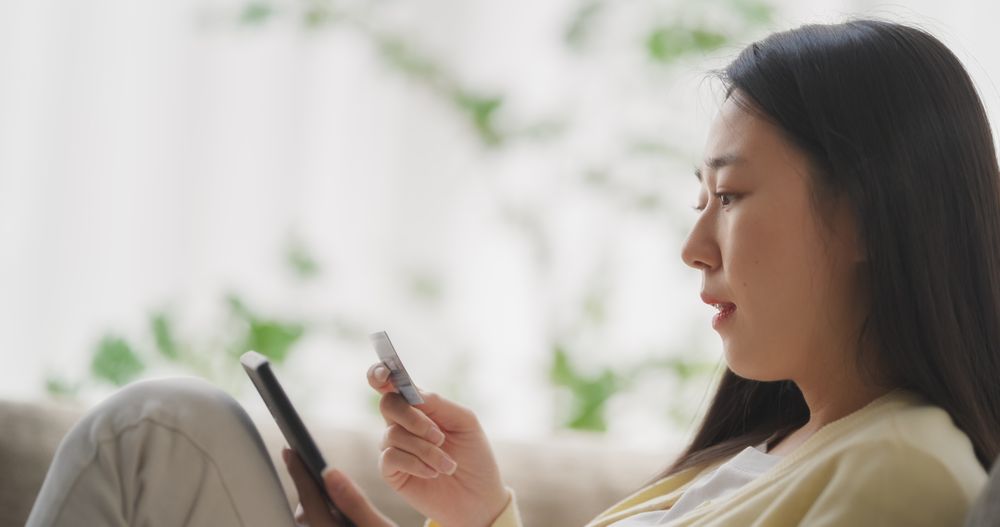 Young South Korean Woman Holding Her Smartphone with One Hand and Credit Card in the Other
