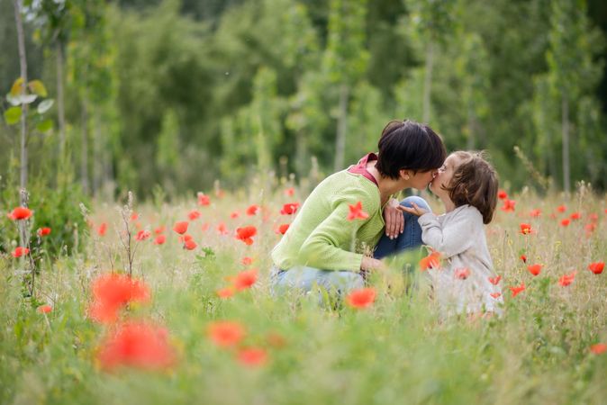 Woman kissing daughter in poppy field
