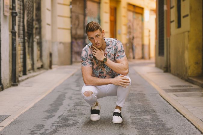 Handsome man sitting on asphalt