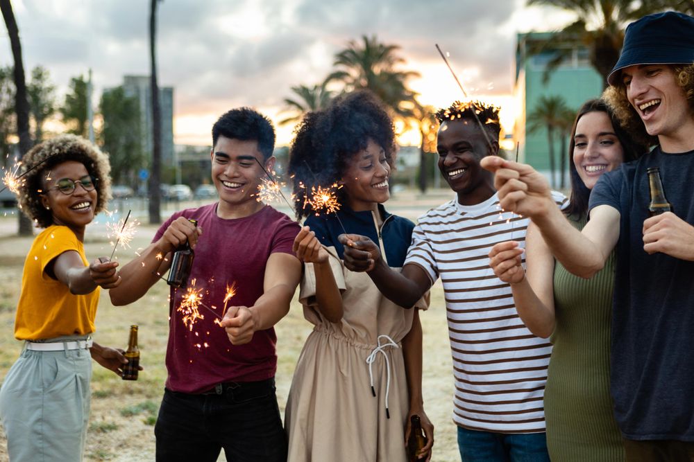 Group of friends with sparklers on the beach at dusk