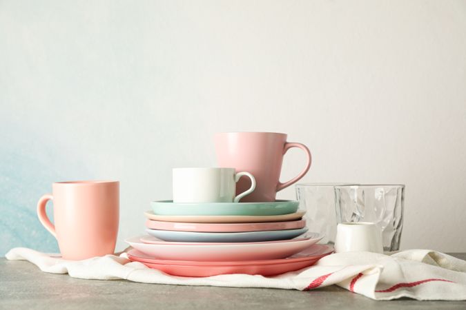 Color plates and cups stacked on grey table, space for text