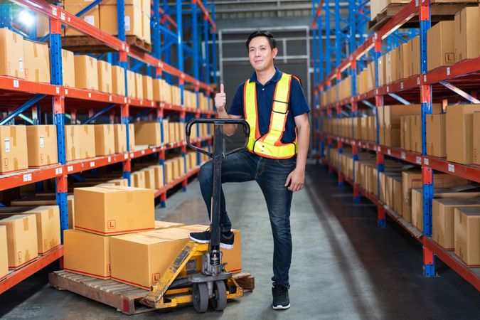 Man working in distribution center with big trolley for boxes