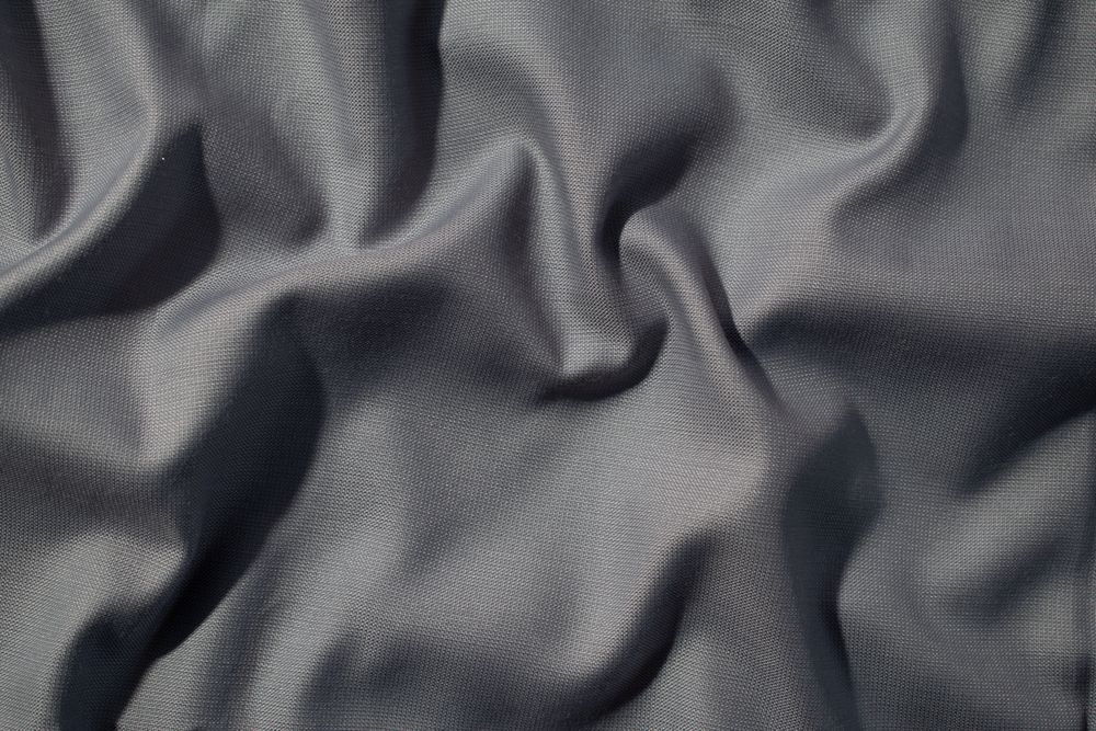 Crumpled wavy dark grey silky fabric background texture. siny and glossy.