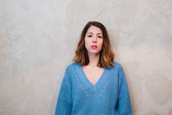 Charming woman in sweater near wall