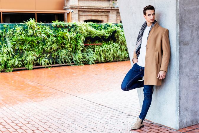 Male wearing winter clothes leaning on wall outside