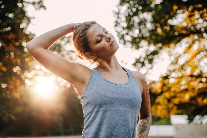 Portrait of healthy young woman stretching her neck outdoors