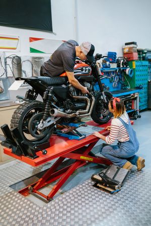 Mechanic team reviewing engine of motorbike on factory