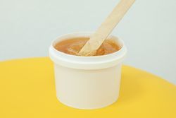 Liquid yellow paste for sugaring on yellow background, space for text