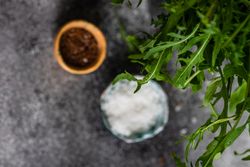 Two small bowls of flax seeds and salt below fresh arugula 