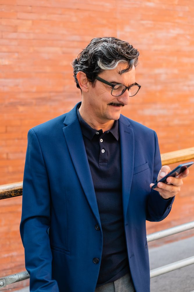 Mature businessman in blue jacket using smartphone