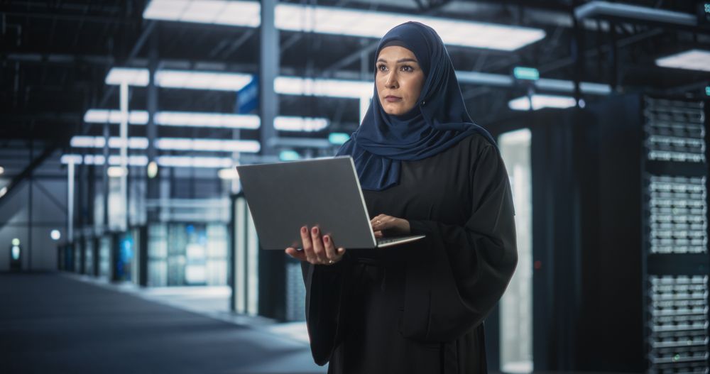 Muslim Female Data Center IT Engineer Standing in a Room with Server Racks.