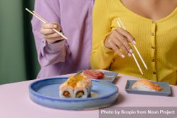 Cropped image of two women sitting beside each other eating sushi 49YPv4