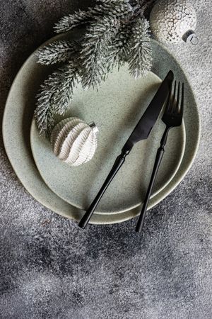 Top view of Christmas table setting with pine branch and snowy baubles