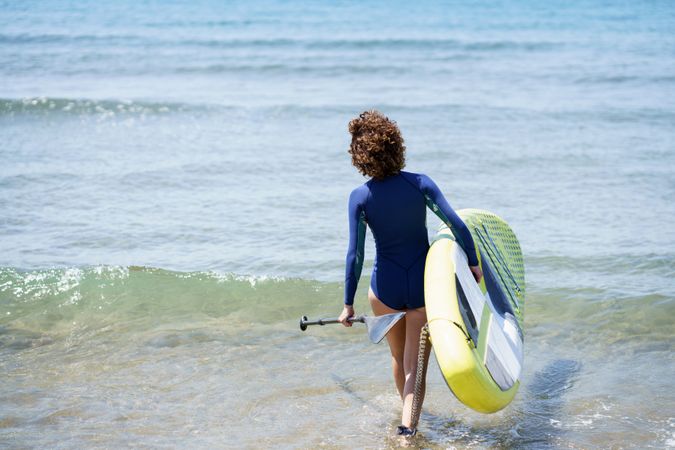 Unrecognizable female surfer with paddleboard in sea
