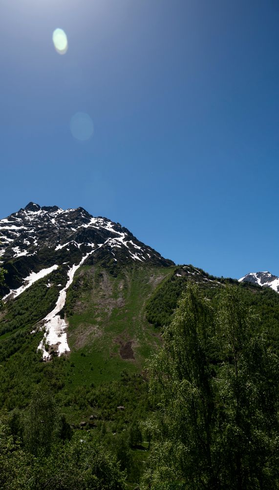 Rocky mountain slope with snow patches and waterfalls