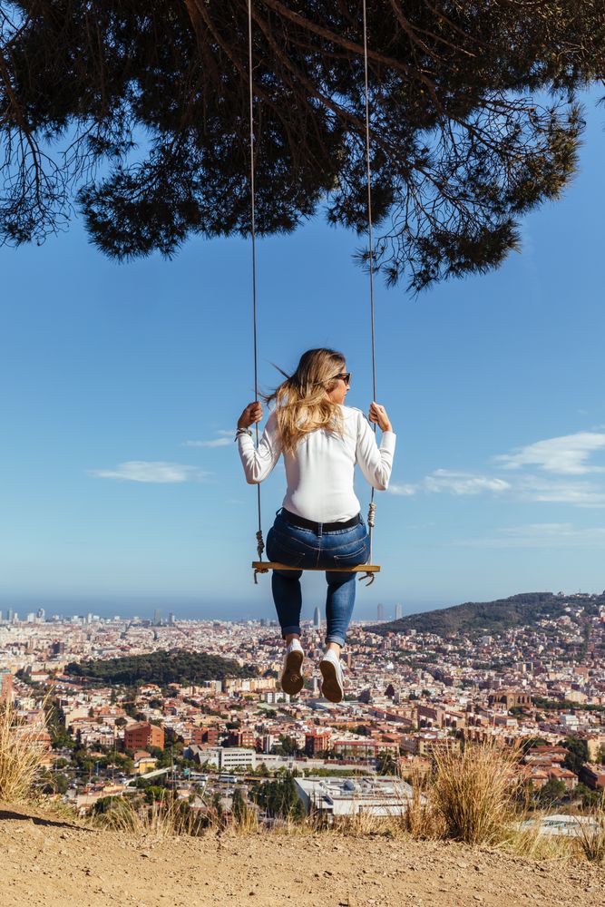 Young female swinging over the city