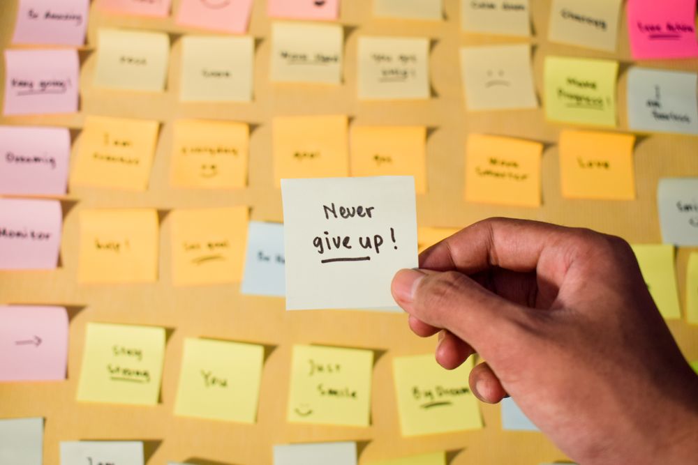 Hand hold sticky notes with words Never Give Up