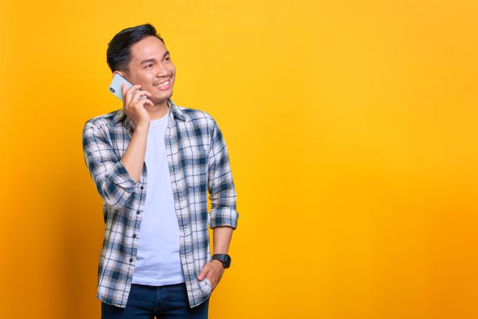 Happy Asian male talking on phone in studio shoot