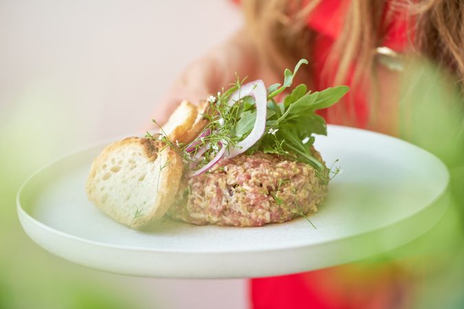 Crop woman with plate of delicious steak tartar