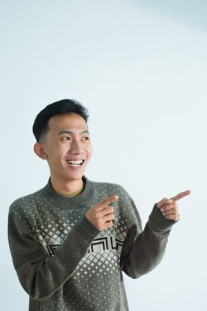 Asian young man pointing to his side in studio shoot
