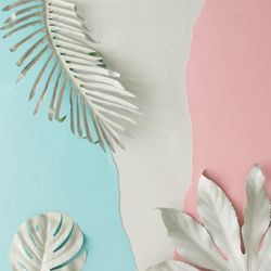 Pieces of ripped pastel colored paper in pattern with tropical leaves